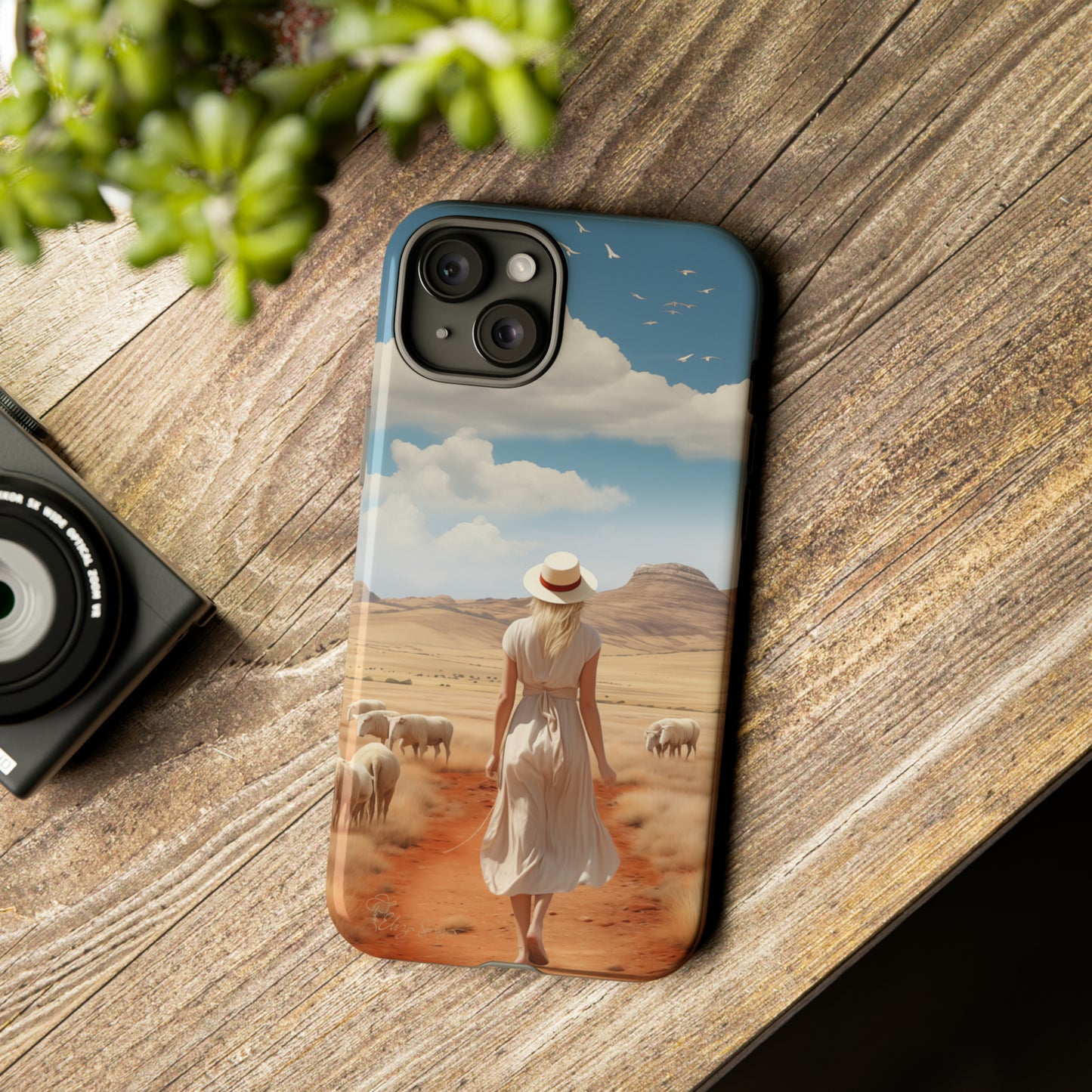 Serenity in Hand: Our Tough Western Cell Phone Case invites you to experience tranquility. A vintage painted design portrays a woman in a skirt and hat walking on a dirt road through a prairie, with grazing sheep. Let the vanishing horizon captivate your senses. Elevate your phone with timeless beauty. #ElizaSinger #PhoneCase