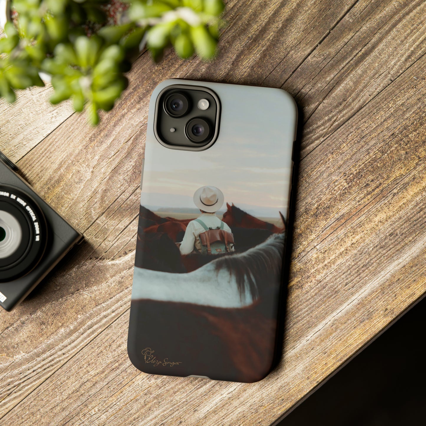 Ride into the Wild: Horse Art Western Photo Yellowstone Design iPhone Tough Protective Cover. Featuring a Cowboy amidst Mountains and Buckskin hues. Compatible with iPhone 15, 14, 13, XS, XR Pro/Max/Mini/P/Plus. Embrace the Spirit of the West with Style and Durability. #ElizaSinger #PhoneCase #WesternDesign