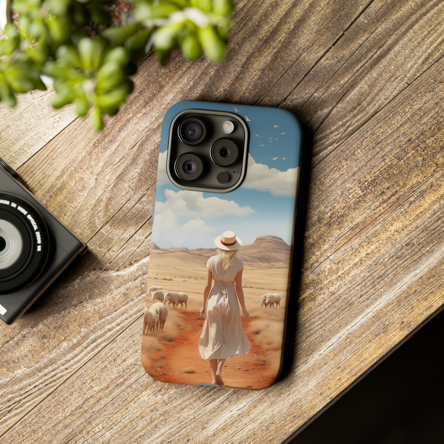 Serenity in Hand: Our Tough Western Cell Phone Case invites you to experience tranquility. A vintage painted design portrays a woman in a skirt and hat walking on a dirt road through a prairie, with grazing sheep. Let the vanishing horizon captivate your senses. Elevate your phone with timeless beauty. #ElizaSinger #PhoneCase