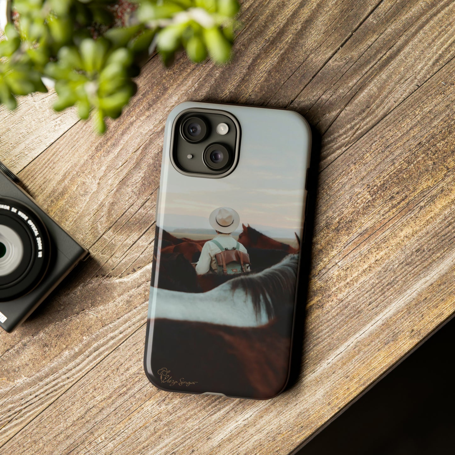 Ride into the Wild: Horse Art Western Photo Yellowstone Design iPhone Tough Protective Cover. Featuring a Cowboy amidst Mountains and Buckskin hues. Compatible with iPhone 15, 14, 13, XS, XR Pro/Max/Mini/P/Plus. Embrace the Spirit of the West with Style and Durability. #ElizaSinger #PhoneCase #WesternDesign