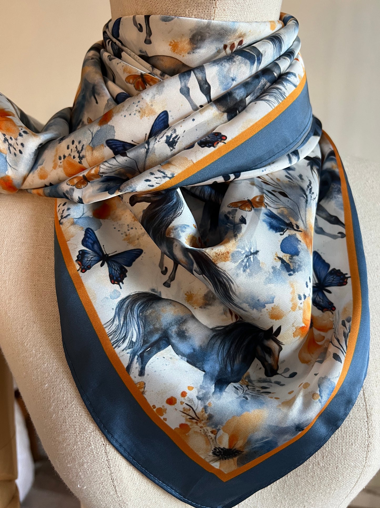 Wings & Whinnies — a dreamy satin silk wild rag featuring galloping horses and butterflies. Designed on the diagonal and signed by Eliza Singer.