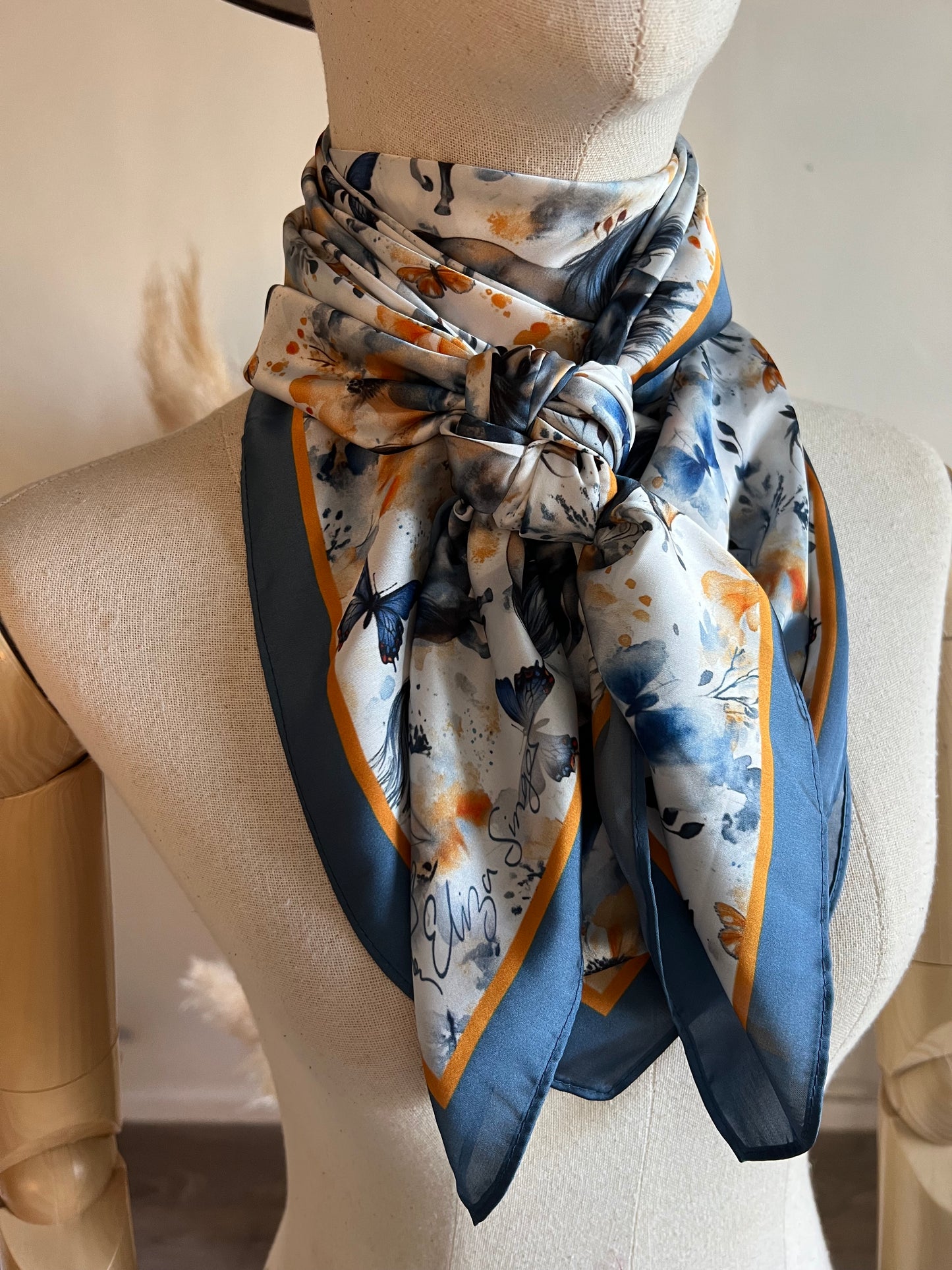 Wings & Whinnies — a dreamy satin silk wild rag featuring galloping horses and butterflies. Designed on the diagonal and signed by Eliza Singer.
