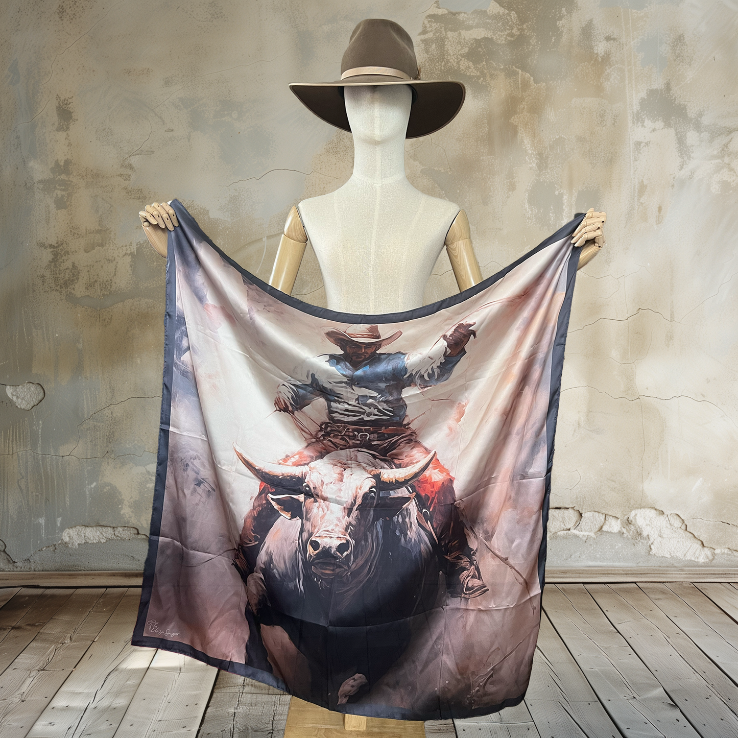 Capture the essence of the rodeo with Bullrider Serenity Wild Rag. A watercolor painting-style bullrider in serene grey tones graces this 39" square of
100% satin silk. Elevate your Western style with this artistic and captivating accessory.