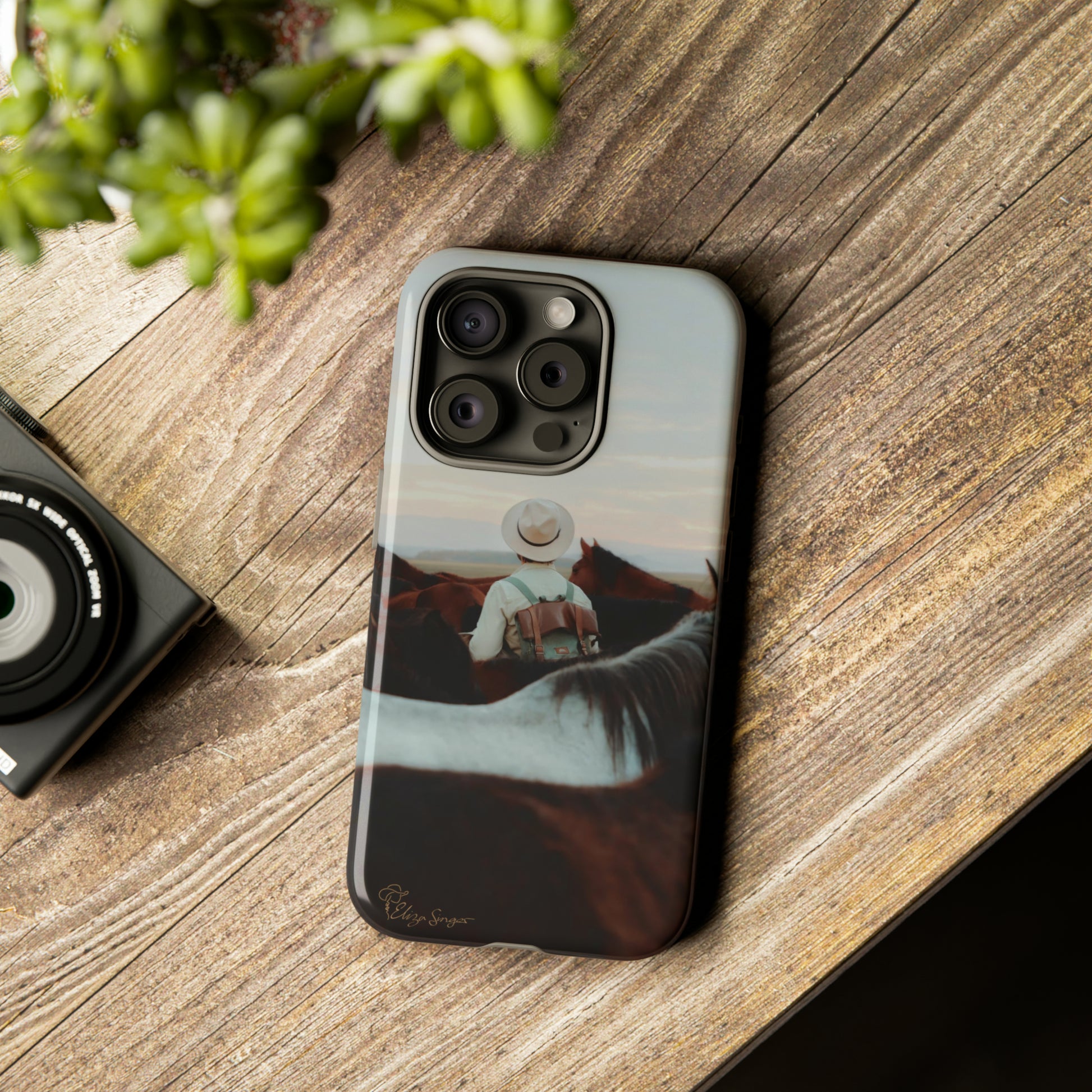 Ride into the Wild: Horse Art Western Photo Yellowstone Design iPhone Tough Protective Cover. Featuring a Cowboy amidst Mountains and Buckskin hues. Compatible with iPhone 15, 14, 13, XS, XR Pro/Max/Mini/P/Plus. Embrace the Spirit of the West with Style and Durability. #ElizaSinger #PhoneCase #WesternDesign