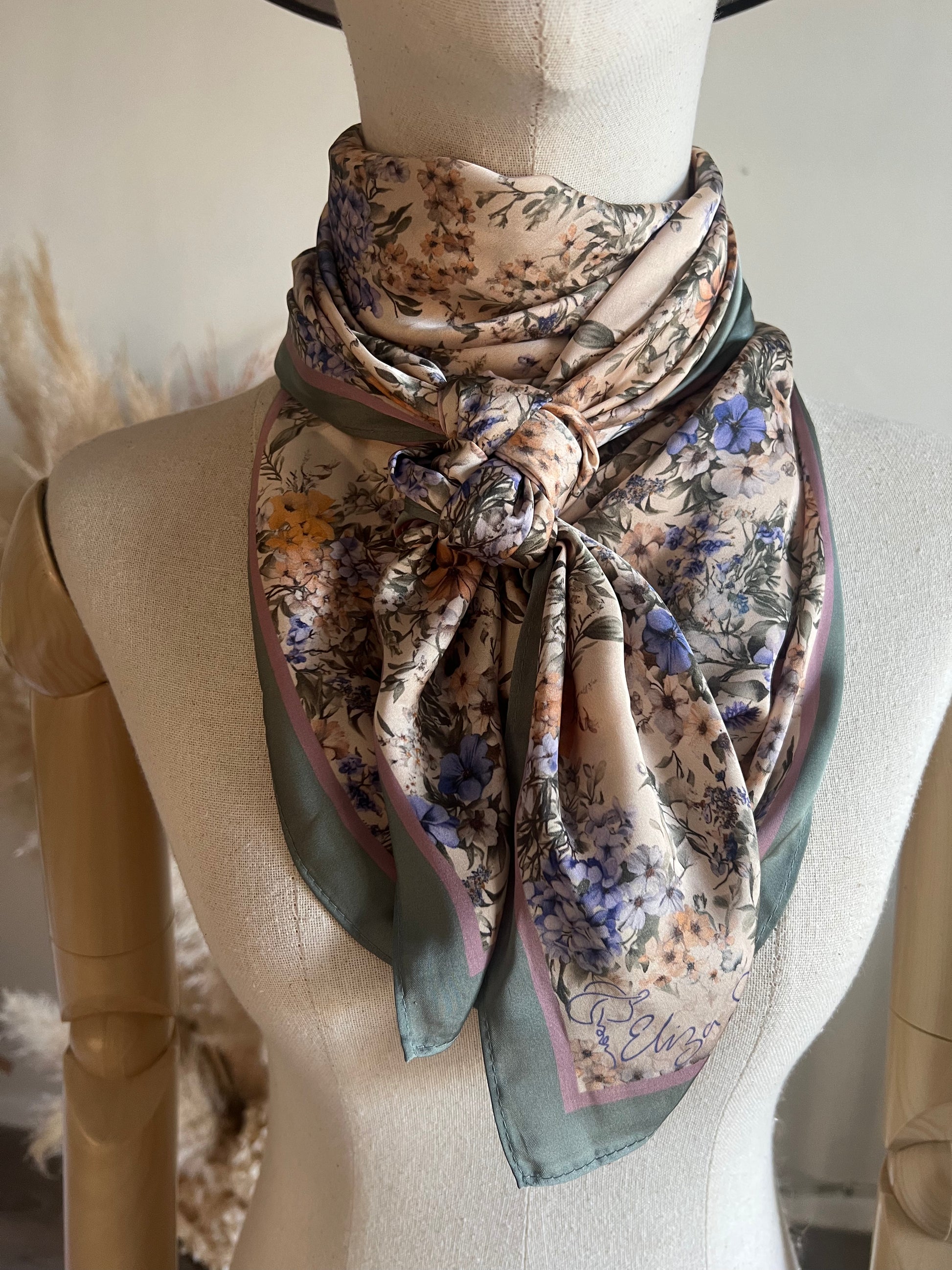 A timeless floral satin wild rag by Eliza Singer. Soft vintage blossoms in lavender and blue on ivory — signed and exclusive.