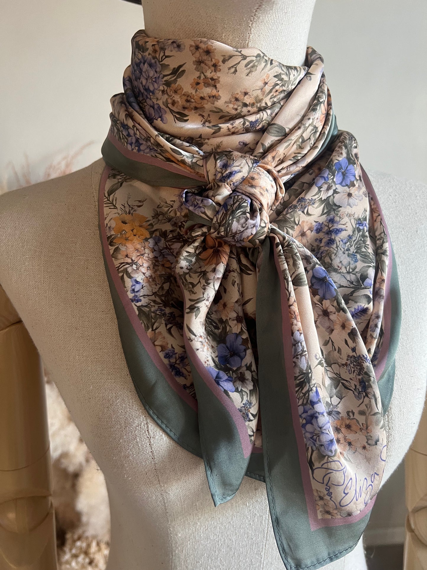 A timeless floral satin wild rag by Eliza Singer. Soft vintage blossoms in lavender and blue on ivory — signed and exclusive.
