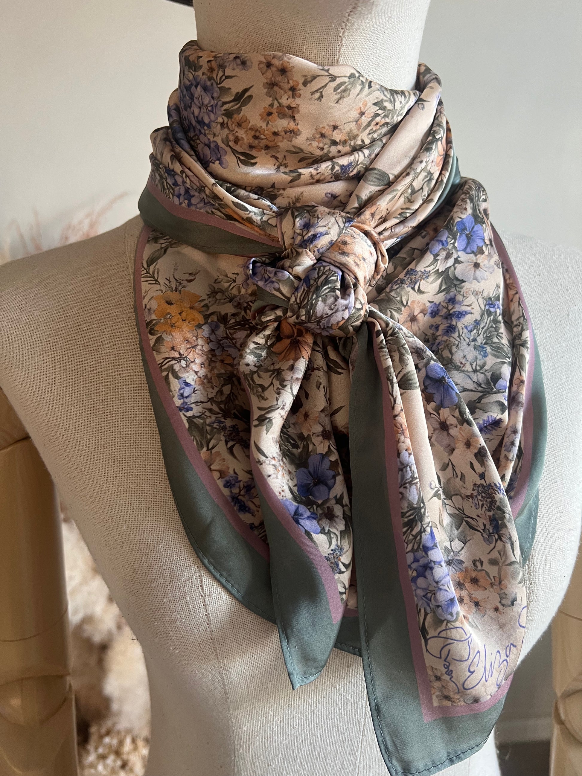 A timeless floral satin wild rag by Eliza Singer. Soft vintage blossoms in lavender and blue on ivory — signed and exclusive.